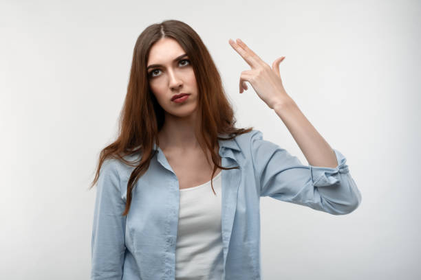 istock Unhappy Young woman tilts head, imitates gun shoot, has puzzled expression. Human emotions concept. 1271492698
