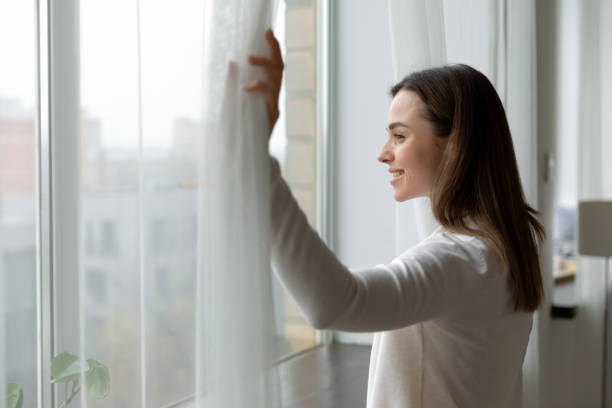 istock Side view happy attractive woman opening curtains. 1271492815