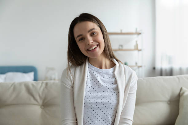 istock Happy young girl sitting on sofa indoors, looking at camera. 1271492816