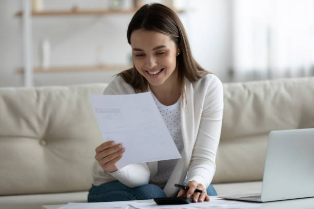 istock Smiling young beautiful woman reading banking paper notification. 1271492864