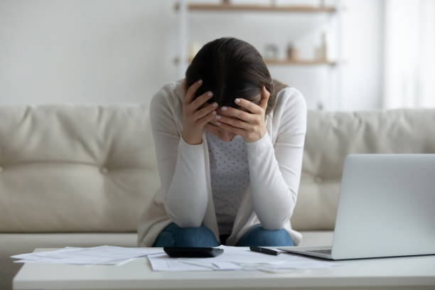 Frustrated young woman feeling stressed about financial problems. Frustrated young woman holding head in hands, feeling stressed about financial problems. Unhappy millennial girl having troubles with managing budget, termination banking letter, bankruptcy concept. money cry stock pictures, royalty-free photos & images