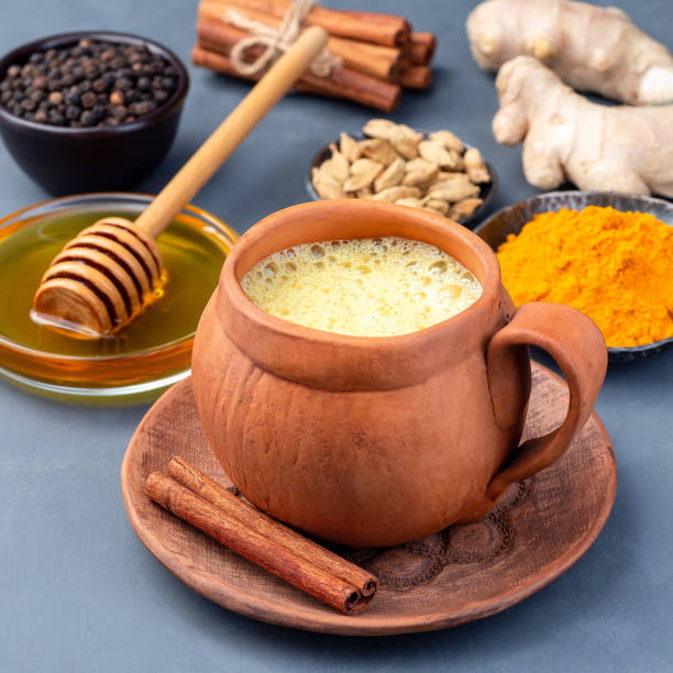 istock Yellow moon milk with turmeric in a clay cup, ingredients on background, square 1271494663