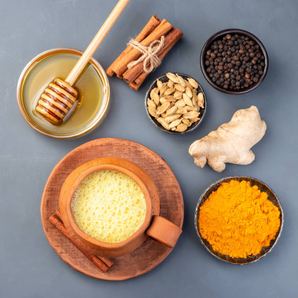 istock Yellow moon milk with turmeric in a clay cup, ingredients on background, top view, square 1271494664