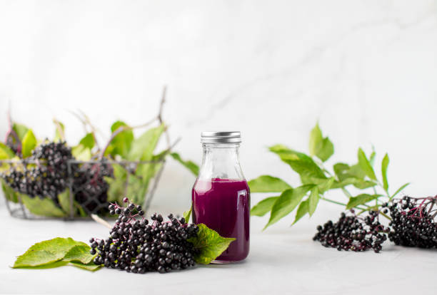 Elderberry syrup in a bottle, front view Elderberry syrup in a bottle, front view of ready to take-in syrup with raw ripe elderberries elderberry photos stock pictures, royalty-free photos & images