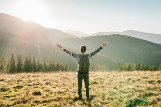 istock Happy man with backpack on sunset in autumn day with open hands. Back view. Hipster enjoying sunrise on peak mountains. Tourist traveler on background valley. Hiker looking sunlight in country Europa. 1271497881