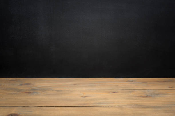istock Empty wooden table against black textured chalkboard for product display 1271498772