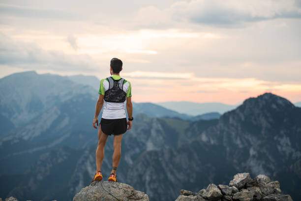 istock mountain running man standing on trail looking at sunset. 1271503850