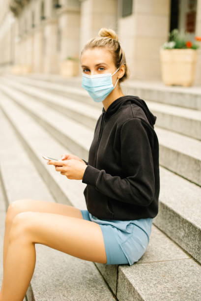 istock Young blonde woman wearing mask using phone. 1271506932
