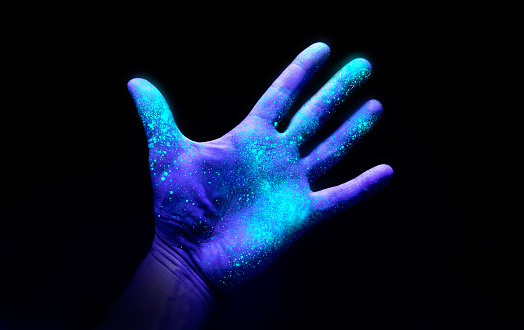 Luz ultravioleta en una mano que muestra el crecimiento de bacterias photo