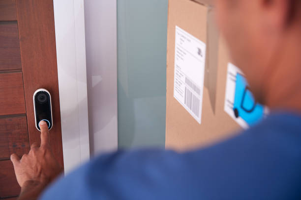 Close Up Of Male Courier Delivering Package To House Ringing Front Doorbell Close Up Of Male Courier Delivering Package To House Ringing Front Doorbell doorbell photos stock pictures, royalty-free photos & images