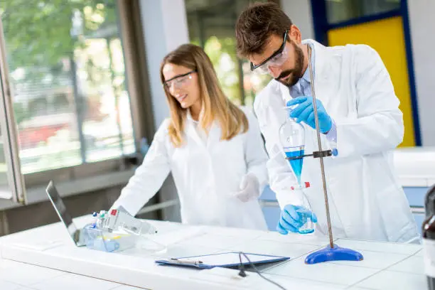 Photo of Researchers working with blue liquid at separatory funnel