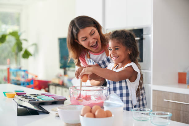 madre e figlia ispaniche che si divertono in cucina a fare la torta insieme - break eggs domestic kitchen breaking foto e immagini stock