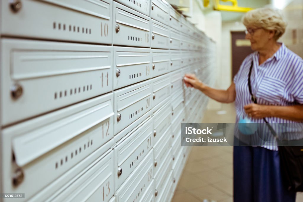Senior woman checking for mailbox Senior woman her mailbox in the apartment. Box - Container Stock Photo
