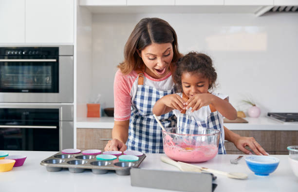 madre e figlia ispaniche che si divertono in cucina a fare la torta insieme - break eggs domestic kitchen breaking foto e immagini stock