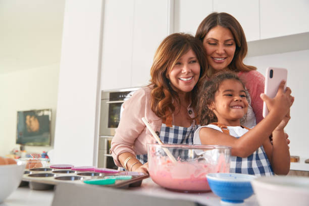wielopokoleniowa hiszpańska rodzina kobiet robiąca selfie podczas robienia ciasta w kuchni razem - multi function zdjęcia i obrazy z banku zdjęć