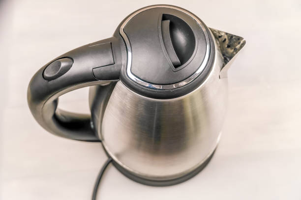Grey and black electric kettle on a light table close-up, top view