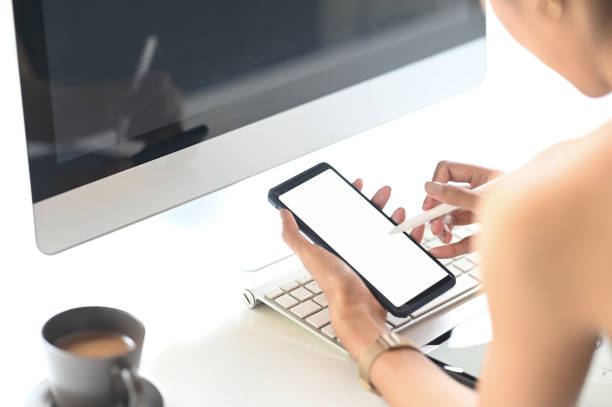 istock Closeup woman holding creative pen and mockup smartphone with empty screen on workspace. 1271515027