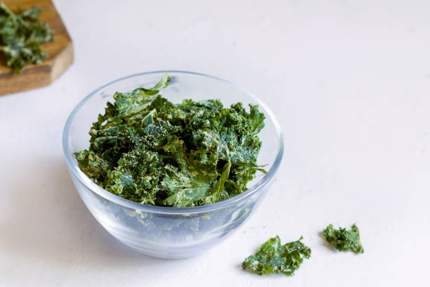 istock Kale chips in a glass bowl on a white background. copy space 1271515112