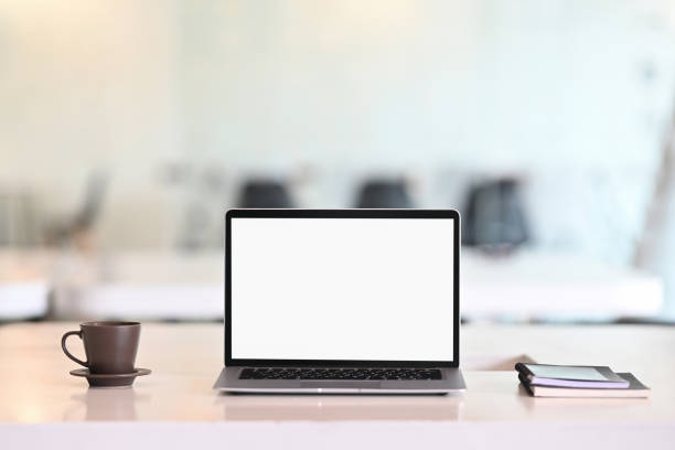 istock Laptop computer, coffee and notebook on business workspace with meeting room blur background. 1271515154