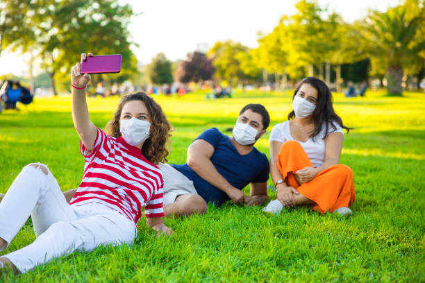 istock Three friends sitting on the grass and taking a selfie 1271515776
