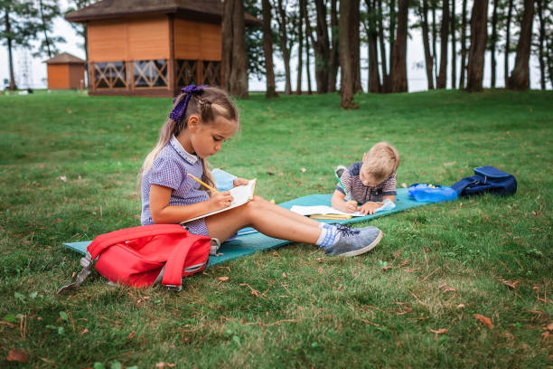 istock Back to school. Elementary scholars sitting on the grass during their open air class 1271516941