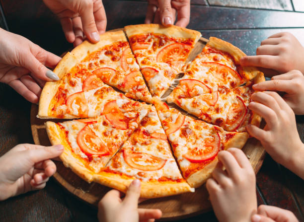 istock Hands taking pizza slices from wooden table, close up view. 1271521867