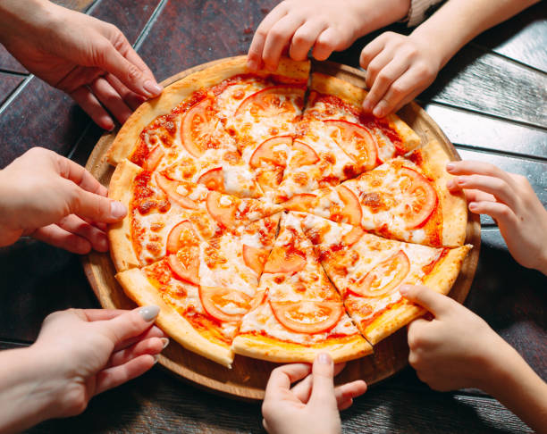 istock Hands taking pizza slices from wooden table, close up view. 1271521909
