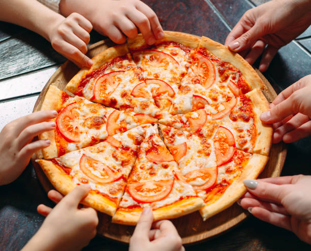 istock Hands taking pizza slices from wooden table, close up view. 1271521919