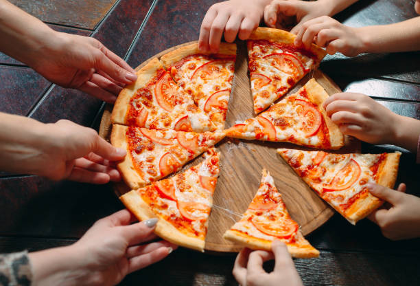 istock Hands taking pizza slices from wooden table, close up view. 1271521943