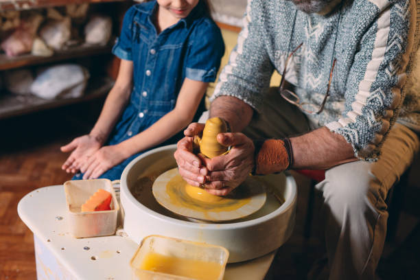 istock Pottery workshop. Grandpa teaches granddaughter pottery. Clay modeling 1271521968