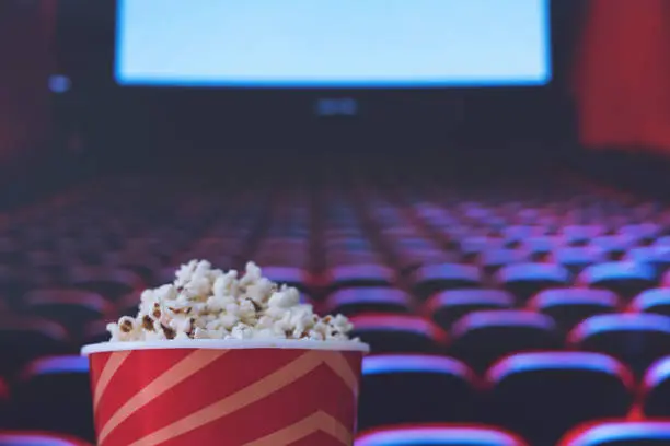 Photo of pop corn and on red armchair cinema