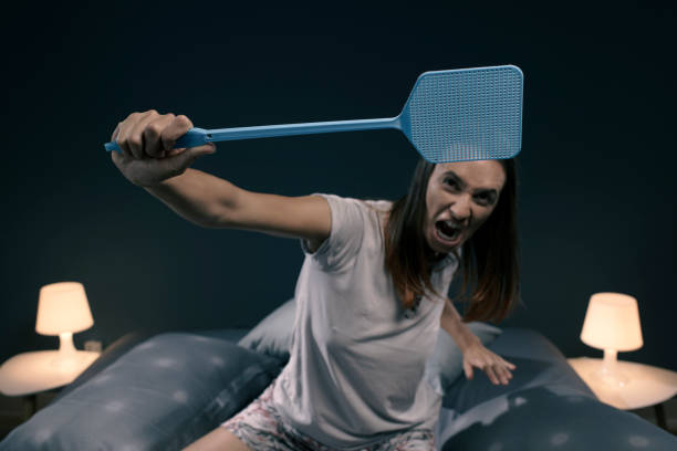 angry woman killing mosquitoes with a fly swatter - aggression control clothing image type imagens e fotografias de stock