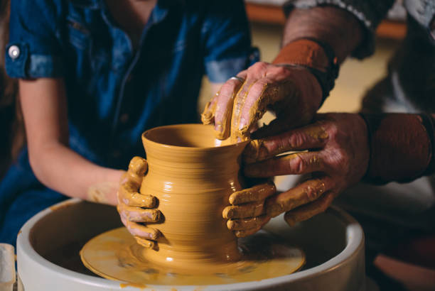 istock Pottery workshop. Grandpa teaches granddaughter pottery. Clay modeling 1271524304