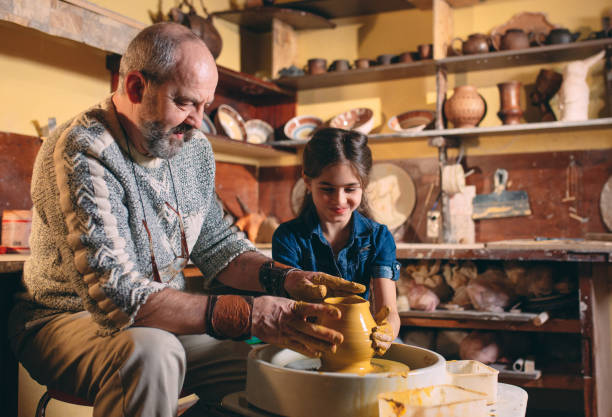 istock Pottery workshop. Grandpa teaches granddaughter pottery. Clay modeling 1271524372