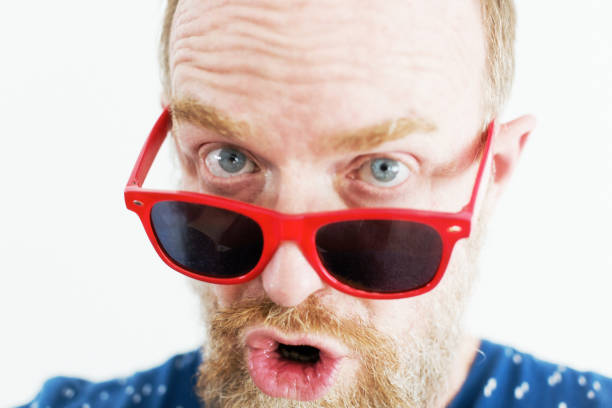 istock Shocked man looks over his red sunglasses with a humorous expression 1271524469