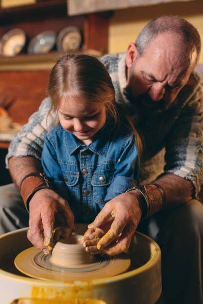 istock Pottery workshop. Grandpa teaches granddaughter pottery. Clay modeling 1271525731