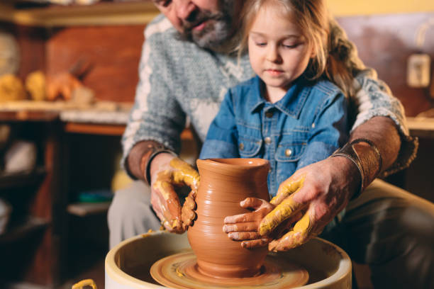 istock Pottery workshop. Grandpa teaches granddaughter pottery. Clay modeling 1271526082