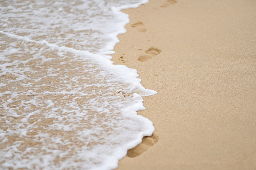 Beach waves covering footprints background