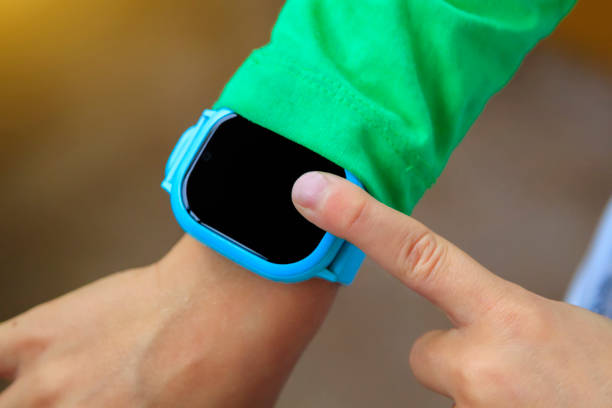 istock boy looks at information on digital clock pressing screen with his index finger. Modern childrens technologies. GPS tracker for kids, child tracking and parental control concept. 1271535236