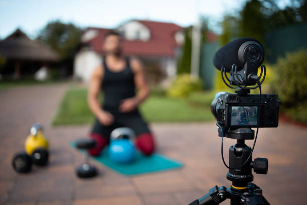 istock Male athlete sitting on exercise mat and making vlog at backyard. 1271537195