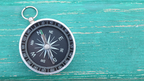 Classic round compass on green wooden vintage background as symbol of tourism with compass, travel with compass and outdoor activities with compass