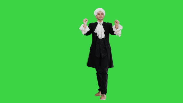 Man dressed like Mozart expressively finishing conducting while looking at camera on a Green Screen, Chroma Key