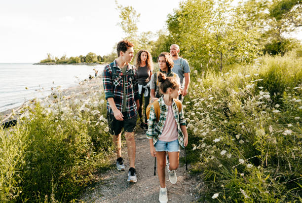 la famiglia caucasica va a piedi in un lago con tre bambini. fratelli davanti a mamma e papà che camminano e parlano. - fourty five foto e immagini stock