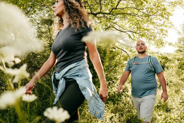 Caucasian couple walking in the park. Young woman and overweight man walking through the woods.