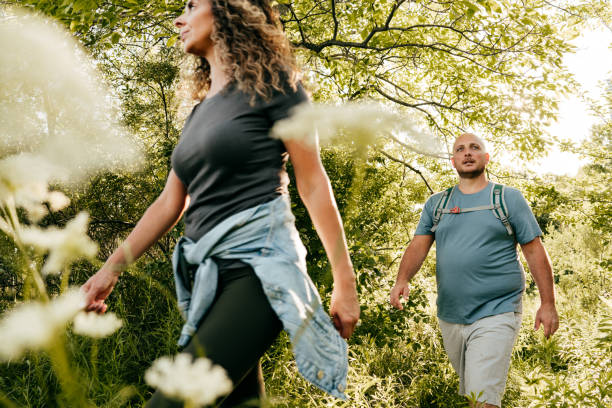 kaukaska para spaceru w parku. młoda kobieta i mężczyzna z nadwagą spacerujący po lesie. - parks canada zdjęcia i obrazy z banku zdjęć