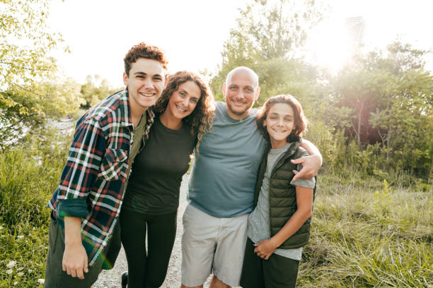 family bonding and having a fun time together. siblings and parents embracing and smiling at the camera. - four people imagens e fotografias de stock