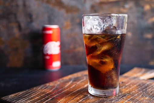 Glass of black soft drinks  and cans of soft drinks