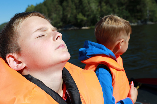 Kid sleeping in life jacket on boat in Ladoga skerries
