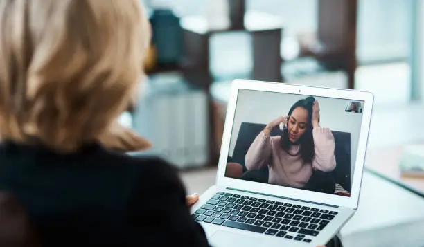 Shot of a young woman having a counselling session with a psychologist using a video conferencing tool