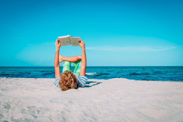 istock boy reading book at beach vacation, summer reading 1271553258